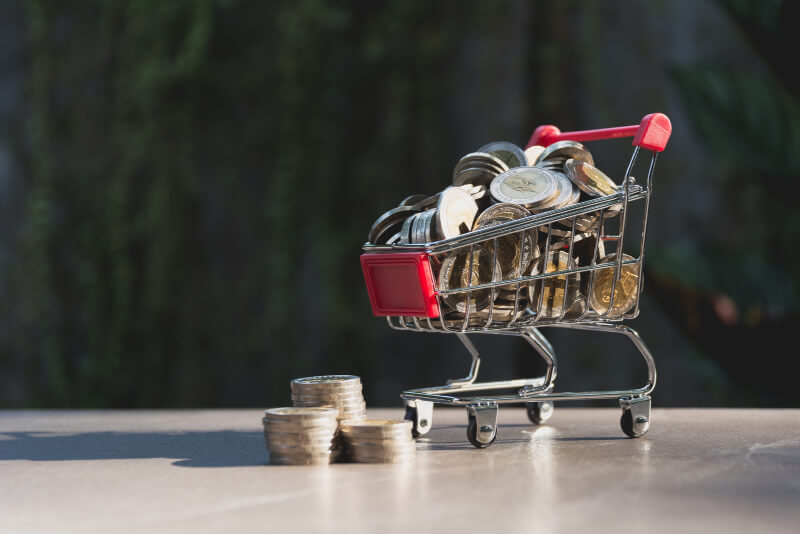 Kleiner Einkaufswagen mit Münzgeld drin, um das Geldsparen beim Lebensmitteleinkauf zu symbolisieren