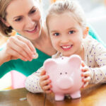 Eine Frau wirft Geld in das Sparschwein ihrer Tochter ein